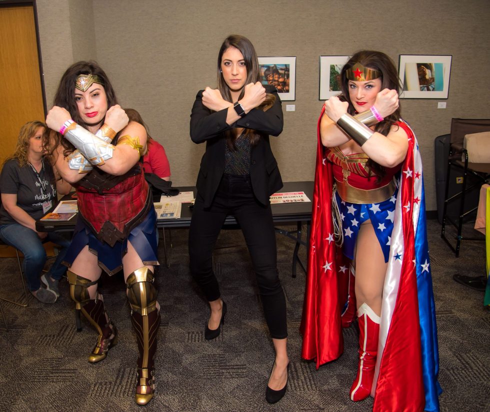 Women posing and throwing up the Wonder Woman symbol in unity. 
