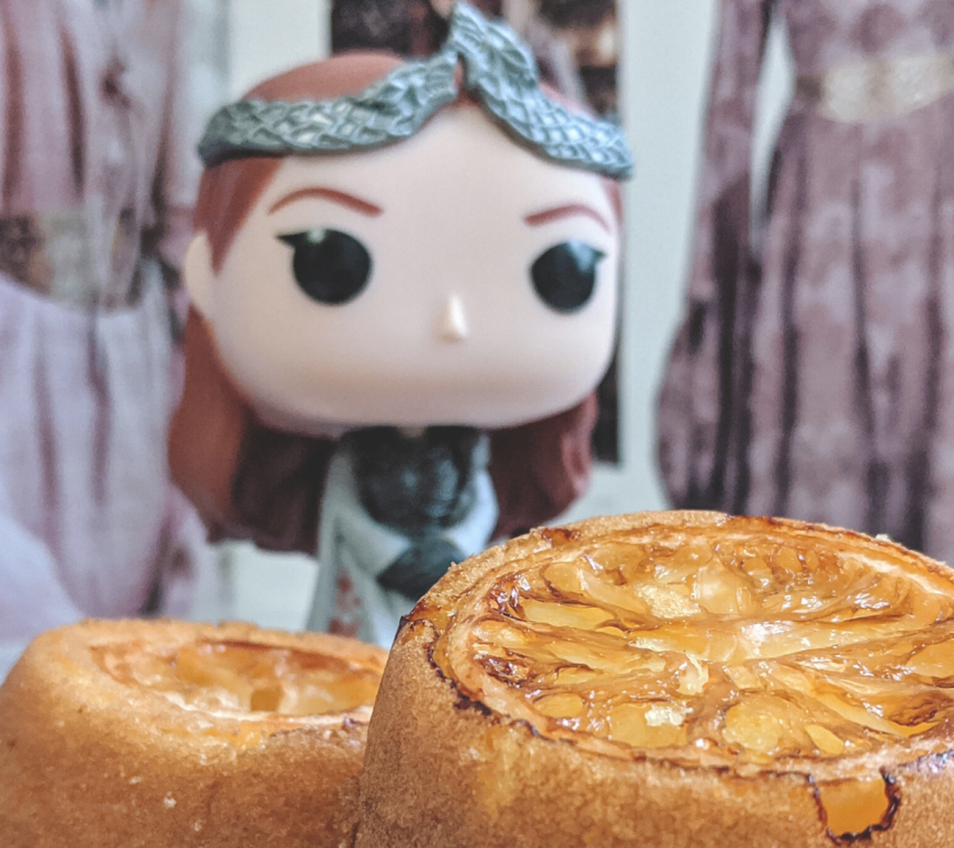 Sansa Stark Funko Pop with two lemon cakes on a marble cheese board
