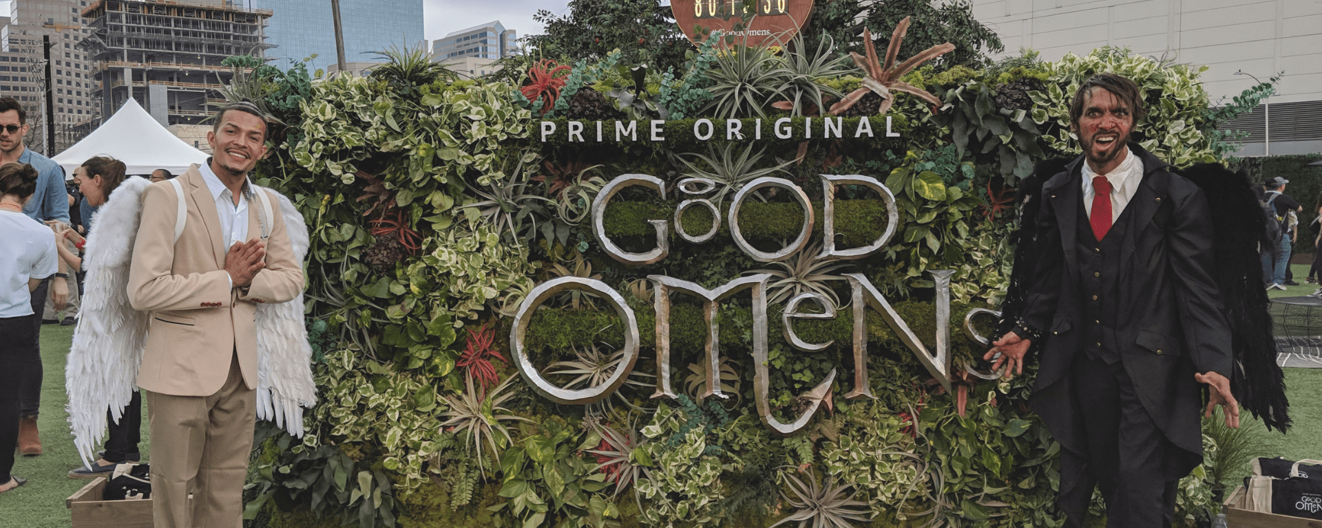 Two people dressed as an angel and a demon welcome visitors to the Good Omens at SXSW: Earthly Garden Delights activation event.