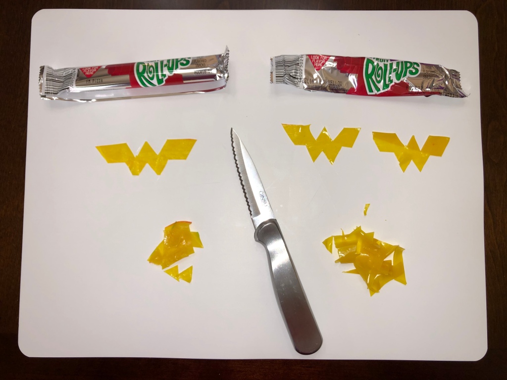 Use a knife (be careful!) to carve out the Wonder Woman "W" logo from the yellow Fruit Roll-Up 