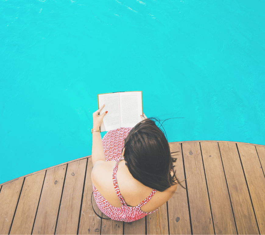 Girl reads a book by the pool