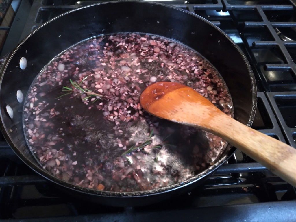 A pot of sauce containing red wine, sake, onions, mushrooms, and rosemary
