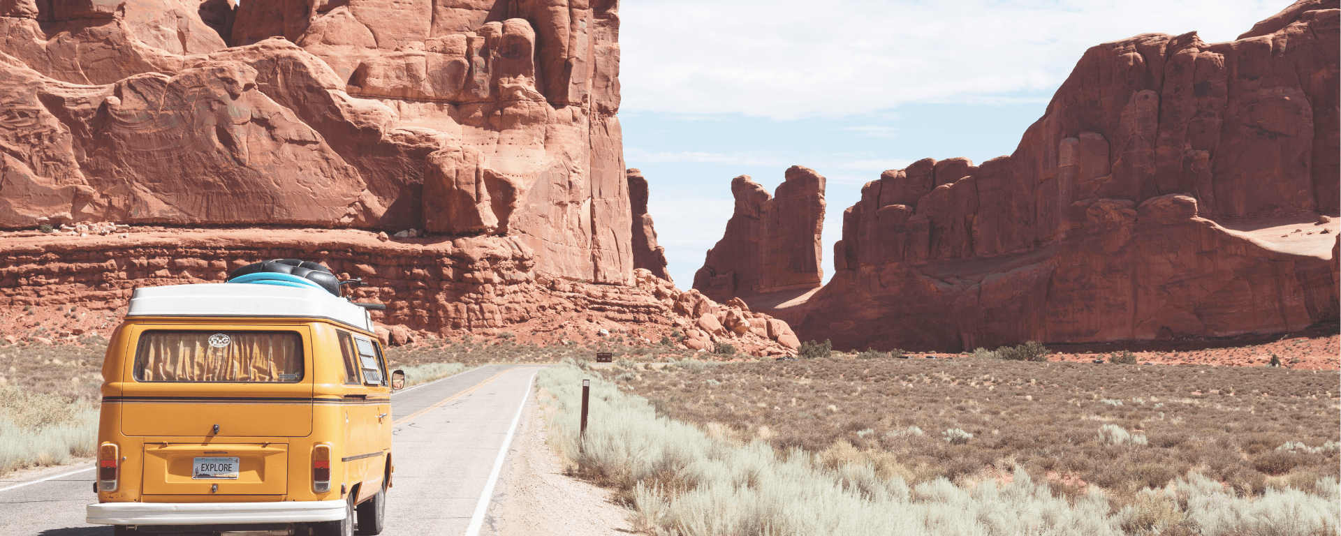 A yellow Volkswagon driving into a canyon, its inhabitants on a road trip.