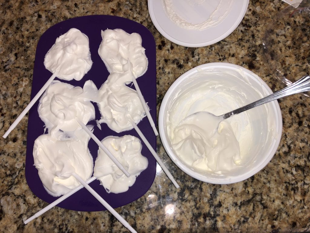 Cool Whip filled into each ghost in the silicone mold with white plastic sticks.