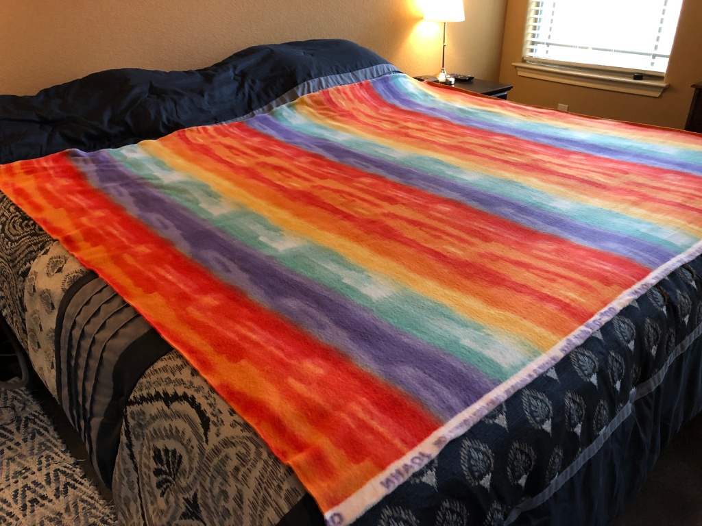 Fleece fabric with a rainbow design laying on a bed